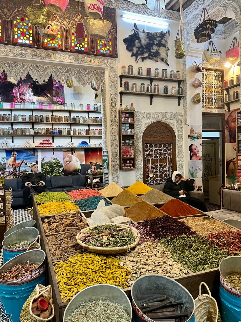 Interior view of a spice shop in the Old Medina of Fez, showcasing colorful spices in large baskets and containers, with a decor featuring traditional Moroccan elements.